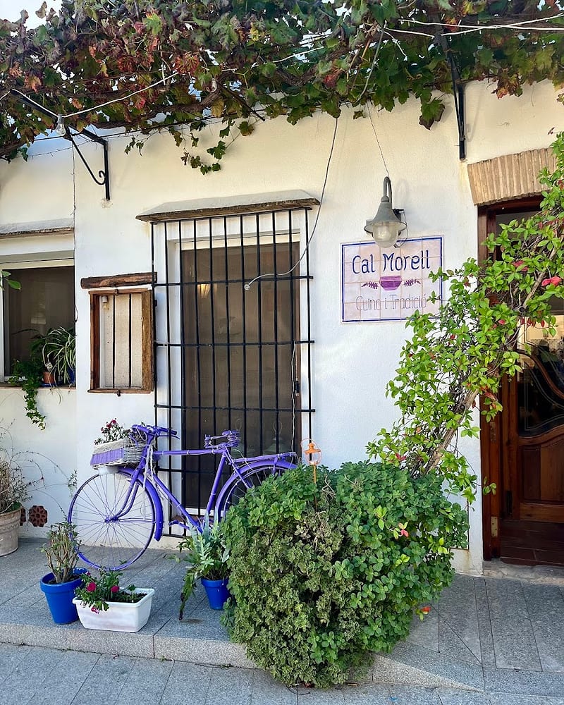 Façana de Cal Morell amb la bicicleta lila i el rètol de ceràmica